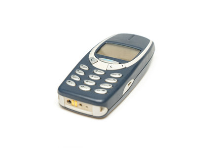 Old dark push-button mobile phone isolated on white background. Mobile phone with buttons.