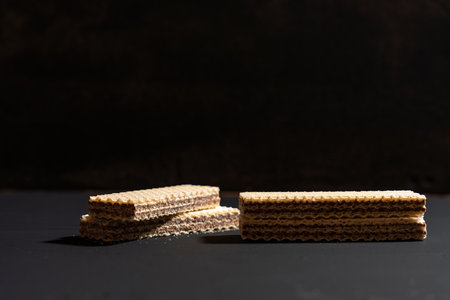 A stack of wafers on a dark background. The wafers are stacked in a pyramid shapeの写真素材