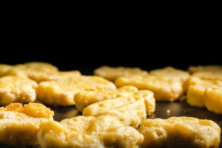 Close-up of golden fried chicken nuggets. The nuggets are arranged in a row, some of them overlap...