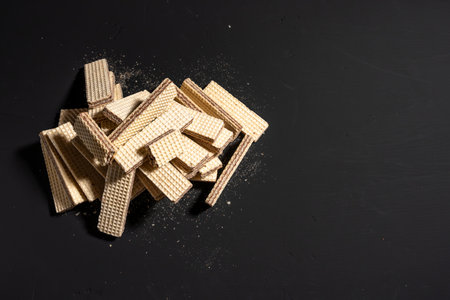 A pile of wafers on a black background. The wafers are in different shapes and sizes, and they are scattered all over the surface.の写真素材