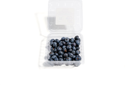 Germany Berlin November 20, 2024. A container of blueberries is open on a white background. The blueberries are in a plastic container and are arranged in a square Berry isolated on white background.のeditorial素材