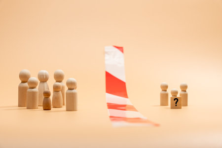 Two groups of wooden figures in the form of people. A large group and a small group with a question mark. Between them is a red and white striped barrier. The concept of finding oneself and finding communication with society.の写真素材