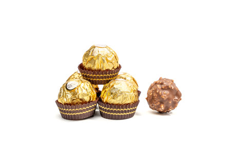 A stack of Ferrero Rocher chocolates with one chocolate on top. Golden colored candies with a chocolate center.のeditorial素材