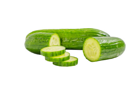 A cucumber is cut into slices and is sitting on a white background. The cucumber is green and has a few slices missingの写真素材