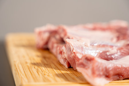 A piece of meat is on a wooden cutting board. The meat is cut into slicesの写真素材