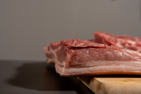 A piece of meat is on a wooden cutting board. The meat is cut into piecesの写真素材
