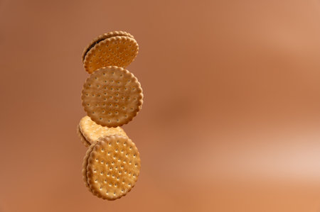Cookies are flying in the air on a brown background. They are all the same size and shape. They are...