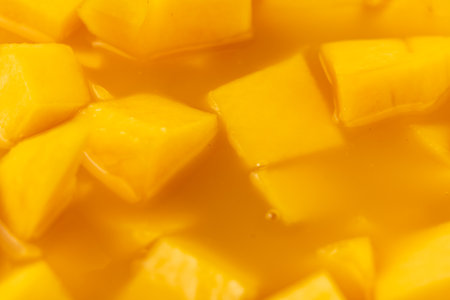 A bowl of sliced mangoes in a yellow liquid. The mangoes are cut into small pieces and are floating in the liquidの写真素材