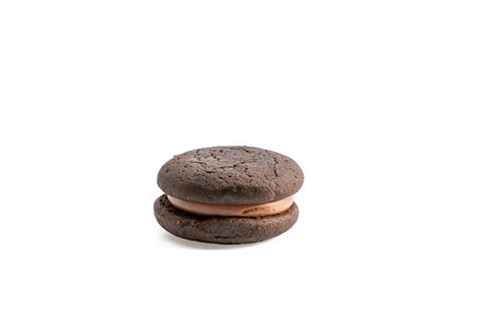 A chocolate cookie with a chocolate filling. It is sitting on a white background. The cookie is round and has a brown colorの写真素材