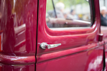 A red vintage car door with a shiny chrome handle, capturing the sleek curves and glossy paint finish. The styling reflects the golden age of automobile design.の写真素材
