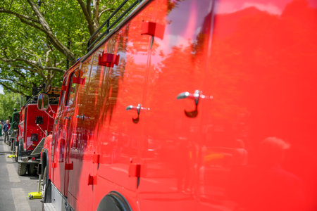 Row of shiny, historic fire engines outdoors in sunshine. Reflections of the surroundings on the paint surface create vibrant colors.の写真素材