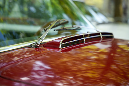 Close-up of a red vintage car. The car with its characteristic air intake and shiny paint under the...