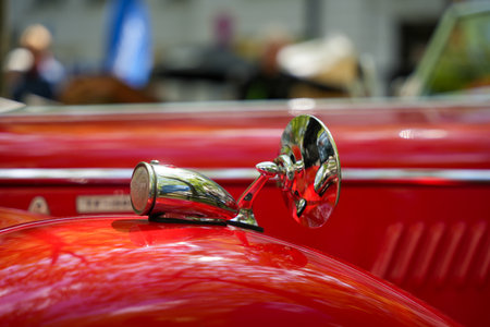 A close-up of a vintage red convertible with an oval side mirror. With a sleek chrome base that catches the shine and reflections.の写真素材