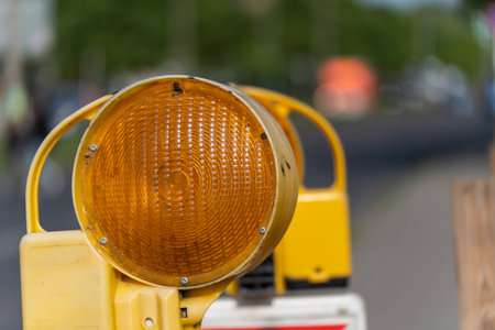 A yellow warning light illuminates a construction site. The light signals caution for road traffic.