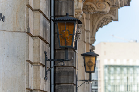 Two ornately decorated wall lanterns adorn an old facade in Berlin. The lanterns create a nostalgic charm and are reminiscent of classic urban furniture.の写真素材