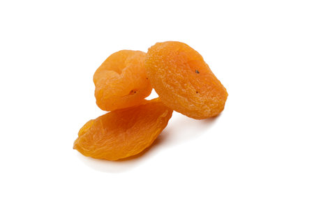 Three dried apricots isolated on a white background. A close-up shot showing texture and color.の写真素材