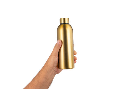 Gold metal thermos bottle in hand isolated on white background. Ergonomic size and smooth surface visible in grip.の写真素材