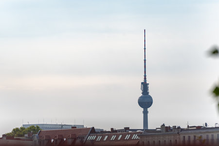 Berlin TV tower above rooftops. The iconic Berlin TV tower rises into the cloudy sky above the city...