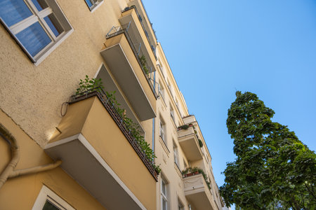 Yellow residential building with balconies and flower boxes. Perspective shot looking upwards against the blue sky.の写真素材