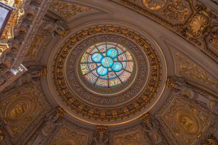 Stained glass dome window inside Berlin Cathedral with Alpha and Omega symbols. Rich golden decorations surround it.の写真素材