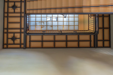 A decorative staircase viewed upward reveals geometric ceiling patterns. A large frosted skylight diffuses natural light.の写真素材