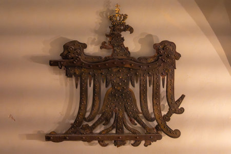 Metal Eagle with Crown. An ornate metal eagle with a crown hangs on a wall. The work has a historic and symbolic feel.の写真素材