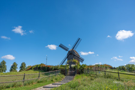 Windmill with Path and Steps - Wide. A path with stone steps leads uphill to a wooden windmill. The...