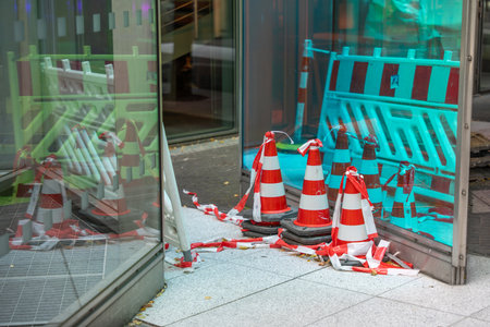 Traffic cones and barriers. Several traffic cones and barrier tape are positioned on a glass facade. Reflections enhance the image.の写真素材