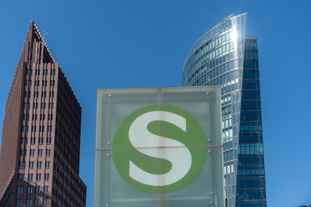 An S-Bahn symbol in front of the skyscrapers at Potsdamer Platz. The green circle shines against a blue sky.の写真素材