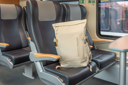 Seat with backpack. A beige backpack rests on a leather train seat beside a table. The interior is modern and ready for travel.の写真素材