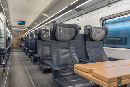 First class seats with table. Two first-class leather seats face a wooden table beside the window....