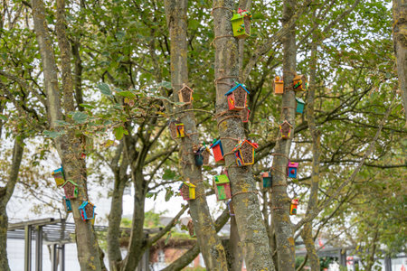 Tree with colorful houses. Trees are decorated with small, colorful wooden houses tied to the...