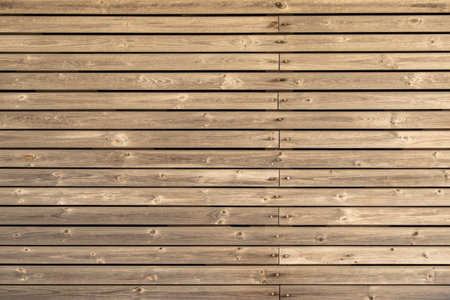 Wooden Wall Texture. Close-up of a wooden wall with horizontal planks and visible screws. The warm...