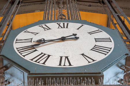 Station clock face close-up. Detailed view of a station clock showing Roman numerals. Weathered...