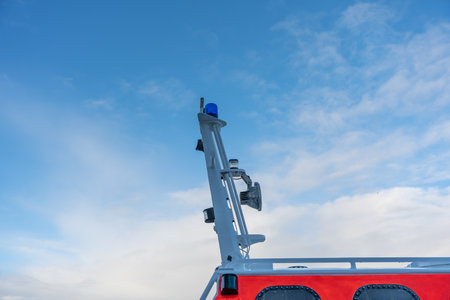 Close view of a rescue boat window with black rivets on red paint. Reflections shimmer across the...