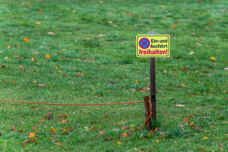 A German sign on green grass reads Ein- und Ausfahrt freihalten. It warns drivers not to block the entrance.の写真素材