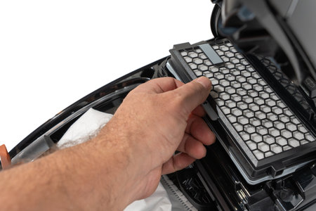 Hand pulls a honeycomb vacuum filter from an open canister compartment for replacement. Close-up...
