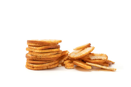 Stacked bread crisps with loose slices beside them on white background. Clean studio composition...