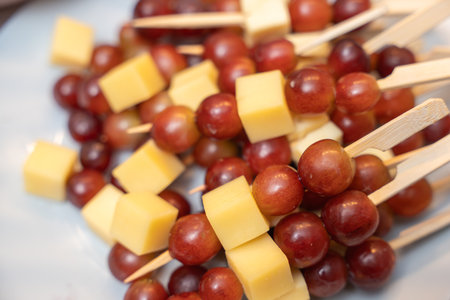 Cheese and Grape Skewers. Cheese cubes and red grapes arranged on wooden skewers. A simple and elegant snack for wine tastings or party buffets.の写真素材