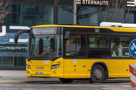 Germany Berlin March 14, 2026. A yellow BVG public bus drives through a Berlin street beside modern...
