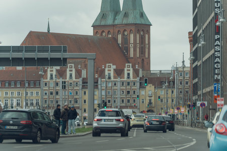 Germany Berlin March 27, 2026. City street flows beneath historic twin spires. People walk calmly,...