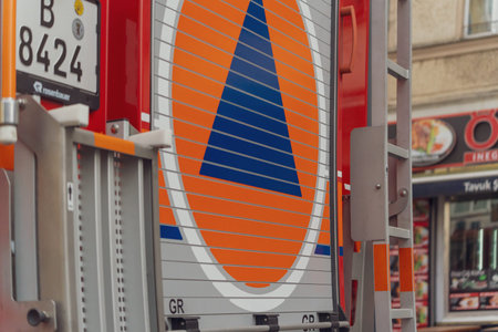 Germany Berlin March 27, 2026. Red fire truck stands beside a building. Large circular sign dominates the truck's side. Blue triangle contrasts with orange background. Metal ladder leans against the vehicle. Sign shows no peopleのeditorial素材