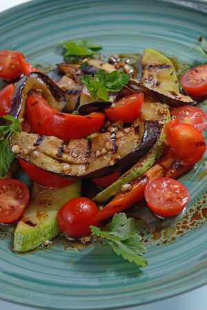 grilled vegetables with cherry tomatoes on a blue plateの写真素材