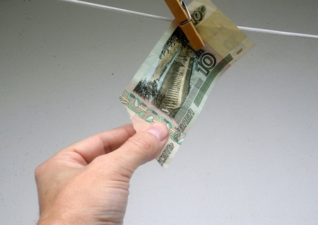 man's hand trying to remove the bill in 10 russian rubles, which hangs on the clotheslineの写真素材