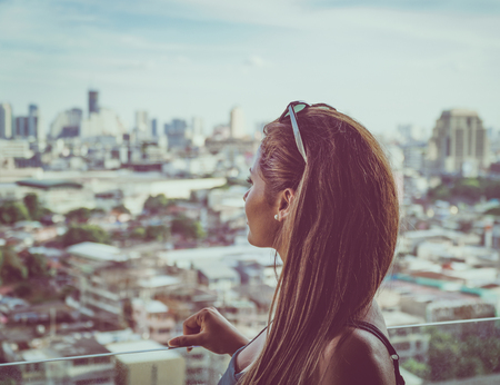 Young female model looking at the city skyline of Bangkok in Thailand.の写真素材