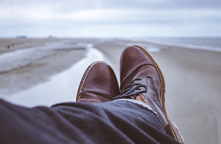 Closeup of leather boots under wool blankets with a stunning view at a northern sea beach.の写真素材