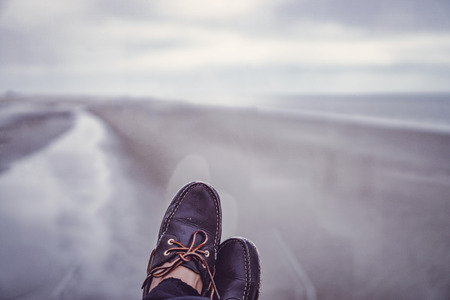 Closeup of leather sailing shoes under with a stunning view at a northern sea beach.の写真素材
