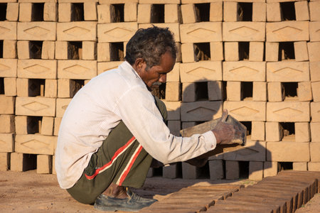 TIKAMGARH, MADHYA PRADESH, INDIA - AUGUST 11, 2021: Indian man making house bricks by hand using a...