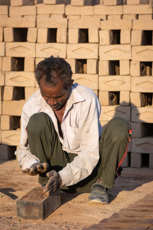 TIKAMGARH, MADHYA PRADESH, INDIA - AUGUST 11, 2021: Indian man making house bricks by hand using a...