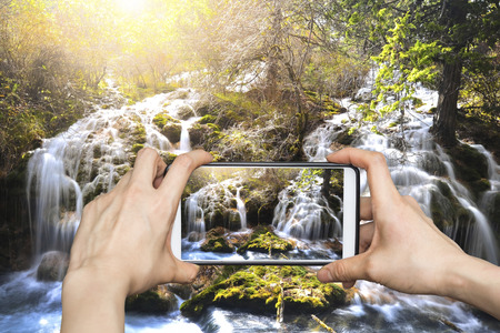 Girl taking pictures on mobile smart phone in Jiuzhaigou National Park,Chinaの写真素材